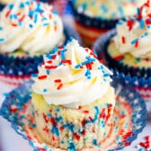 cupcakes with vanilla frosting and with red white and blue sprinkles on top.