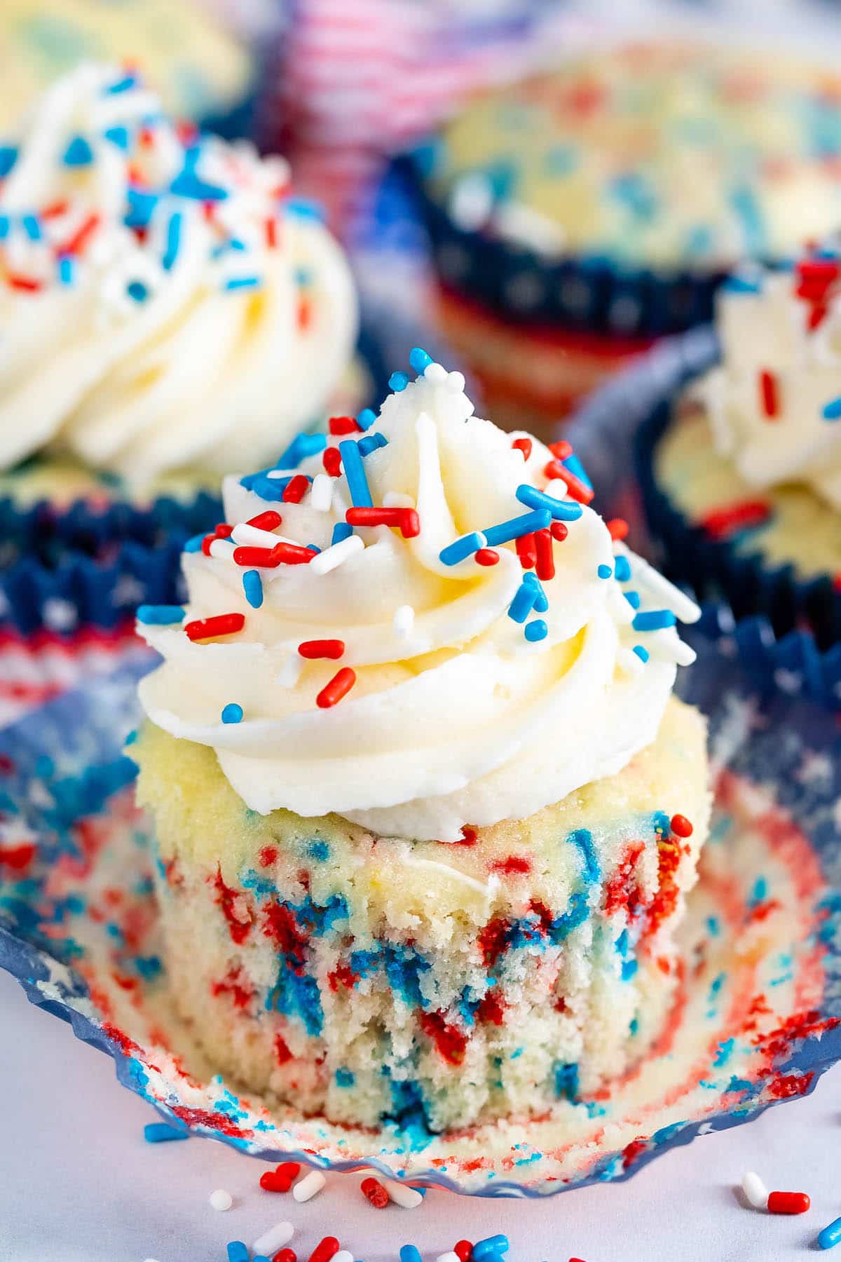 cupcakes with vanilla frosting and with red white and blue sprinkles on top.