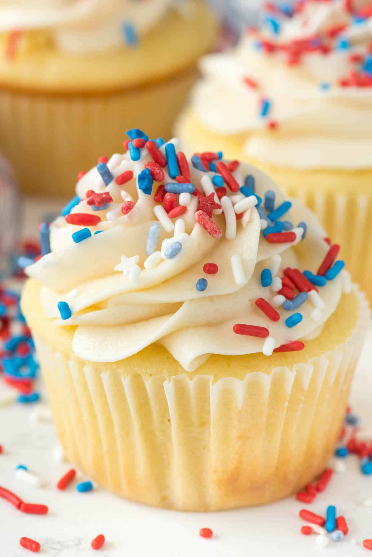 cupcakes covered in red white and blue sprinkles and white frosting.