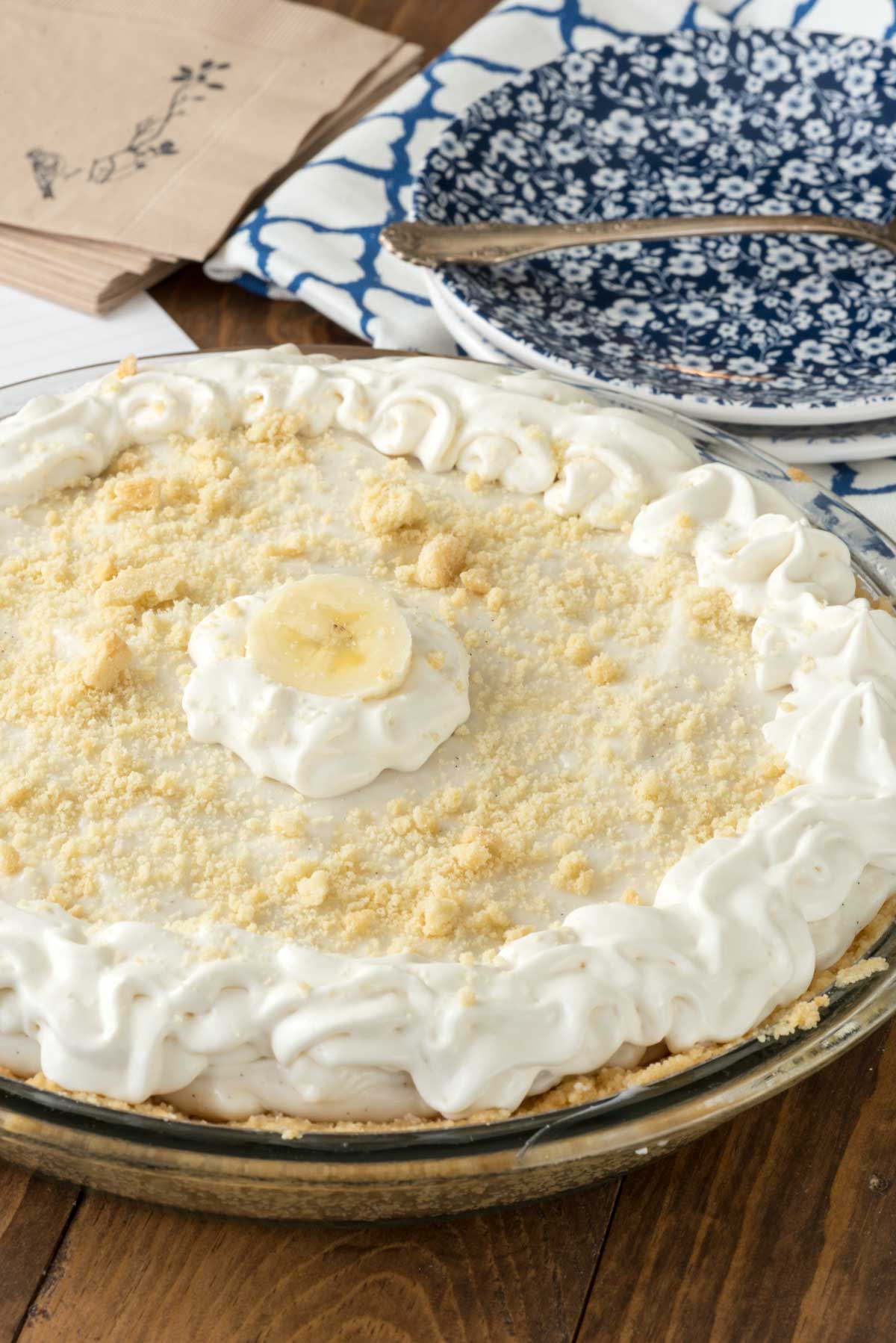 banana pie with a banana slice on top in a clear pie pan.