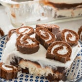 Swiss roll dessert on a plate next to a fork with sliced Swiss rolls on top.