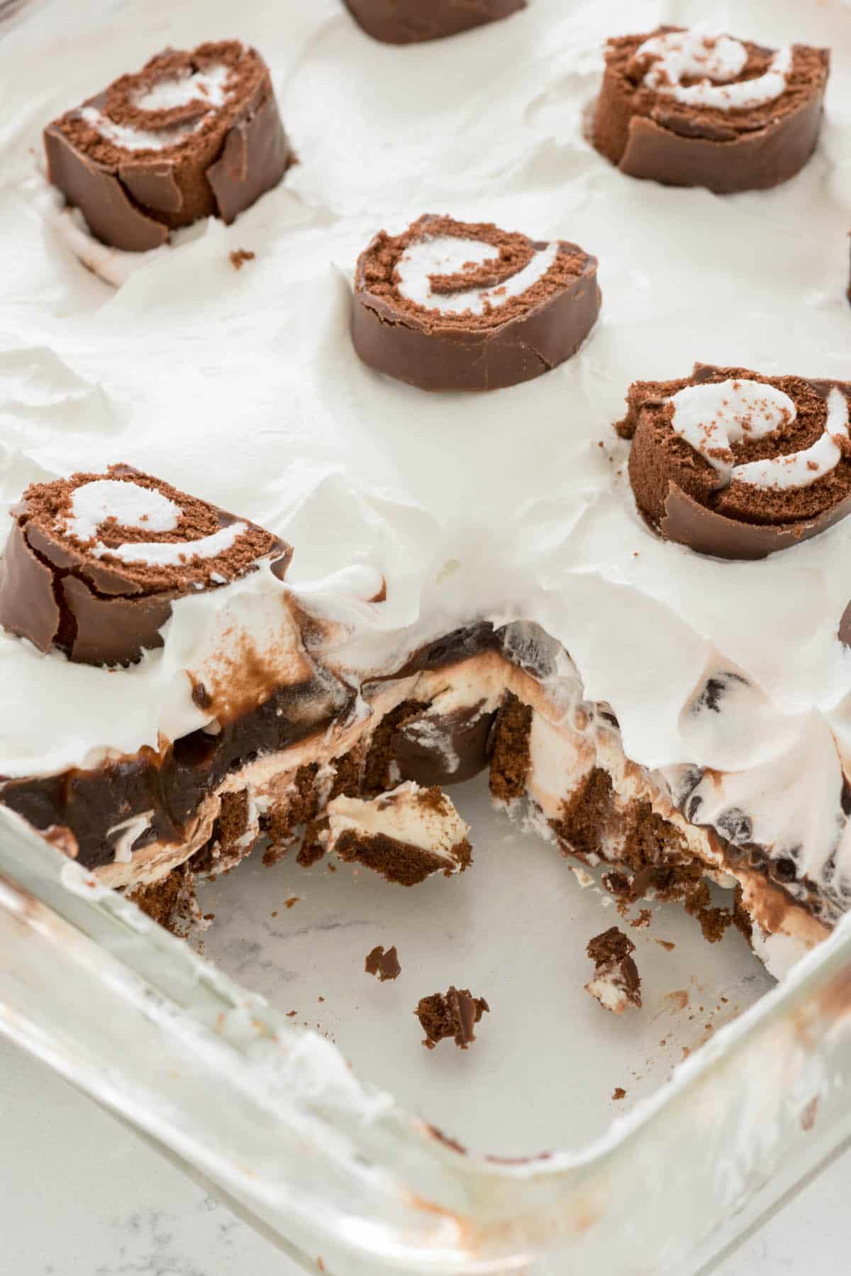 Swiss roll dessert on a plate next to a fork with sliced Swiss rolls on top.