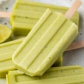 stacked green popsicles with wooden sticks at the bottoms on a white plate