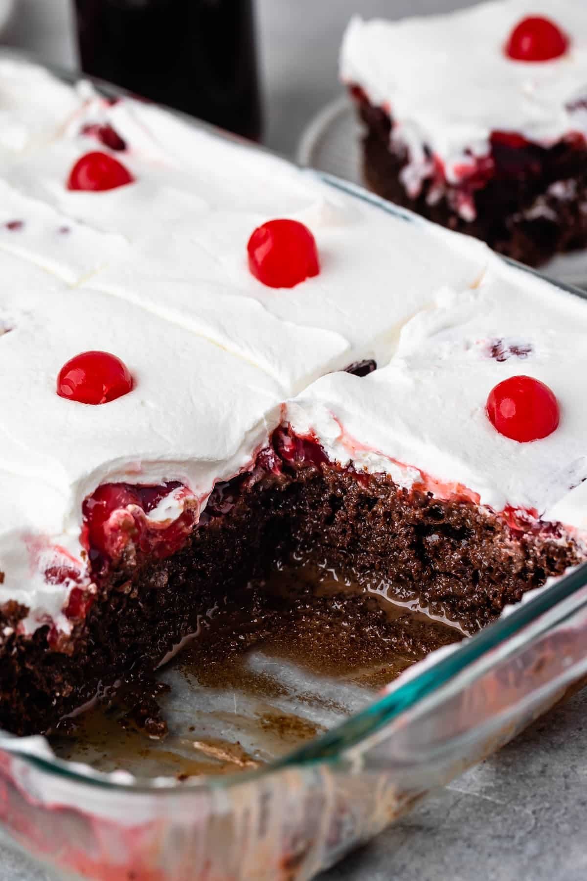 cherry coke cake topped with white topping and a cherry.