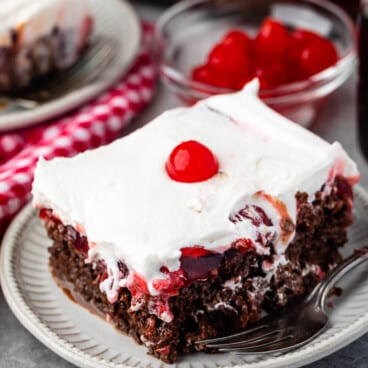 cherry coke cake topped with white topping and a cherry.