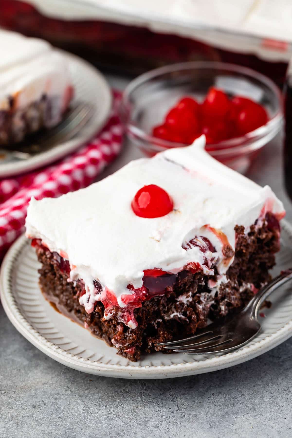cherry coke cake topped with white topping and a cherry.