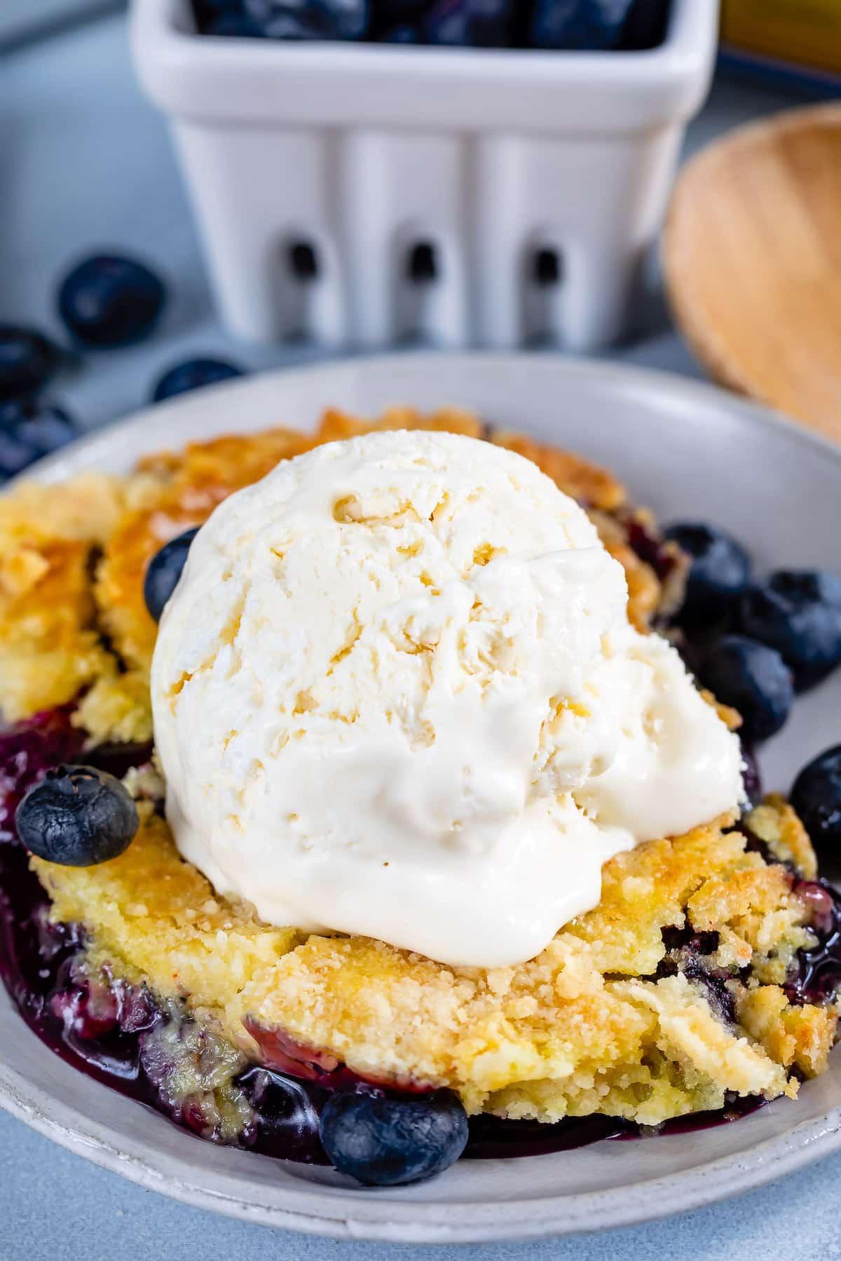 cobbler with a scoop taken out of it in a white glassware with ice cream on top.