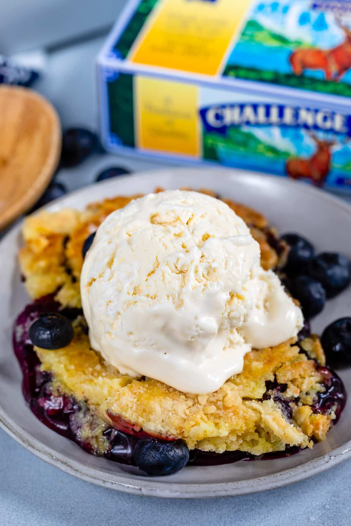 cobbler with a scoop taken out of it in a white glassware with ice cream on top.