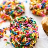 stack of 3 cookies coated in rainbow sprinkles.