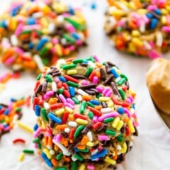 stack of 3 cookies coated in rainbow sprinkles.