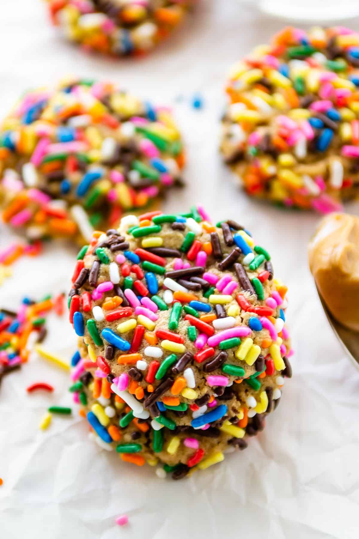 stack of 3 cookies coated in rainbow sprinkles.