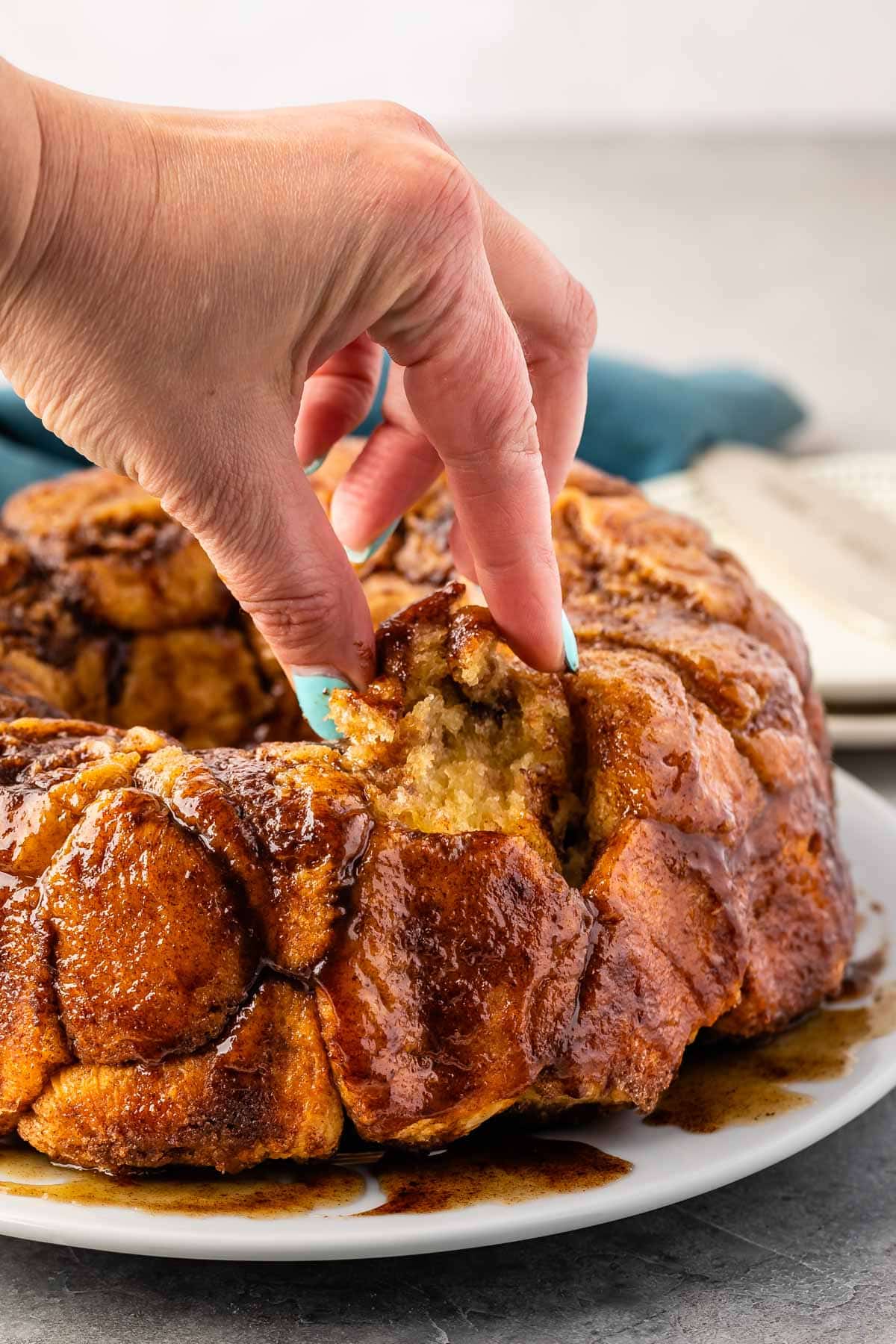 monkey bread on a white plate with a hand holding a piece of it.