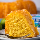 slicer of cake on white plate with fork and limes behind and butter box.