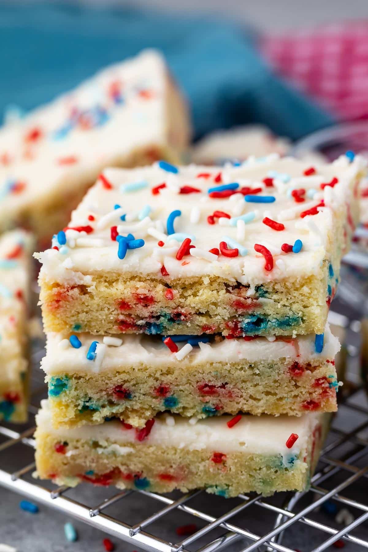 stacked sugar cookie bars with vanilla frosting and red white and blue sprinkles on top.