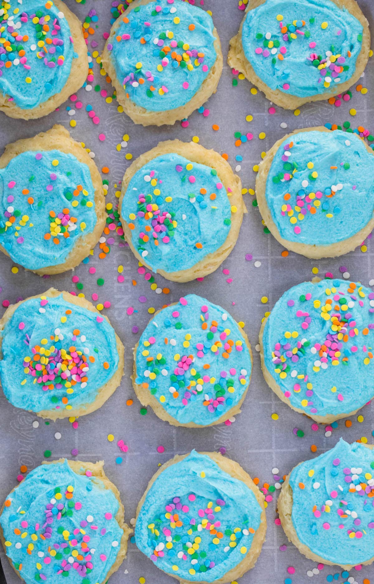 12 blue frosted cookies on cookie sheet