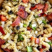 pasta and salami and other mix ins together in a wooden bowl.