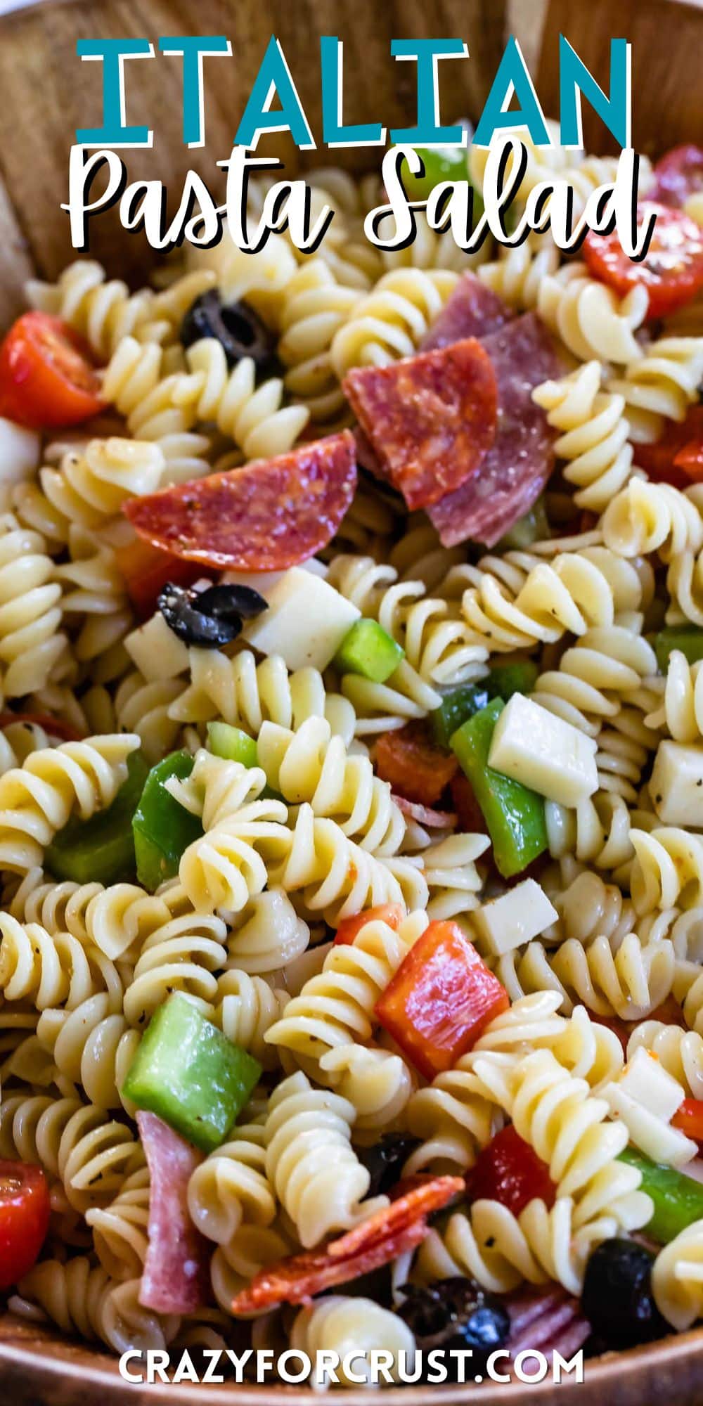 pasta and salami and other mix ins together in a wooden bowl with words on the image.