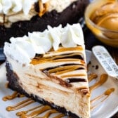 cheesecake with peanut butter and chocolate sauce drizzled over it and whipped cream on the edge.