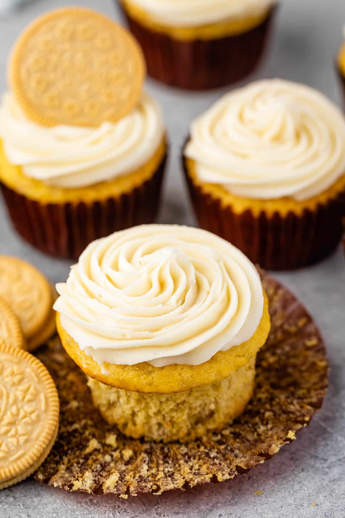 banana cupcakes next to golden oreos with white frosting.