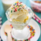 ice cream in a clear cup with white magic shell and sprinkles on top.