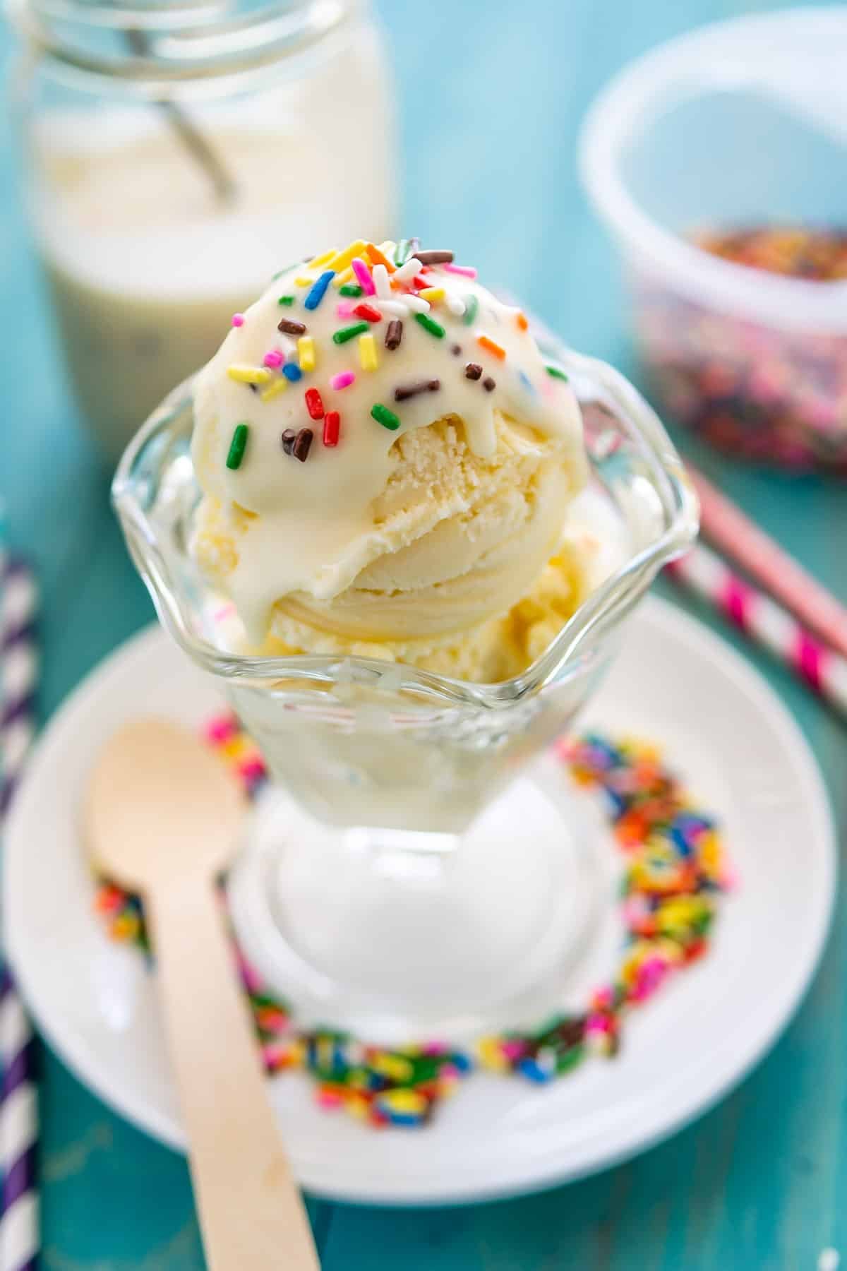 ice cream in a clear cup with white magic shell and sprinkles on top.