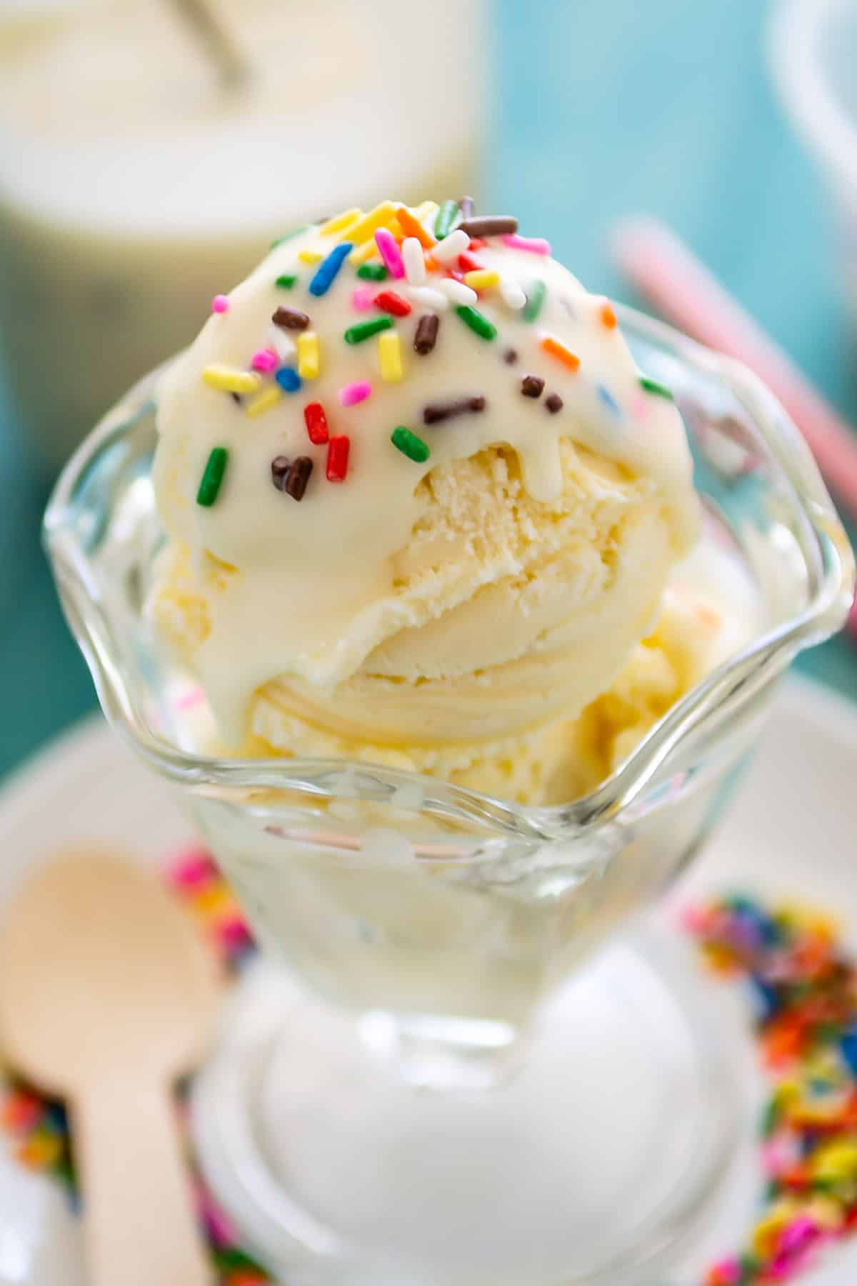 ice cream in a clear cup with white magic shell and sprinkles on top.