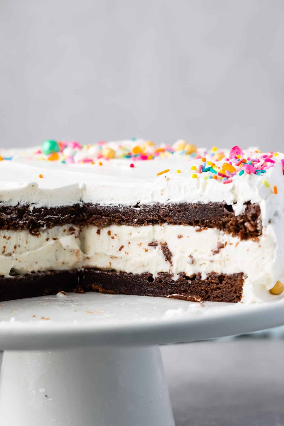 brownie cake layered with ice cream and frosting and topped with sprinkles.