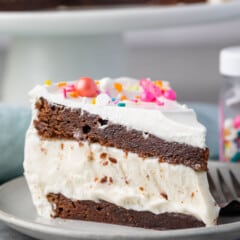 brownie cake layered with ice cream and frosting and topped with sprinkles.