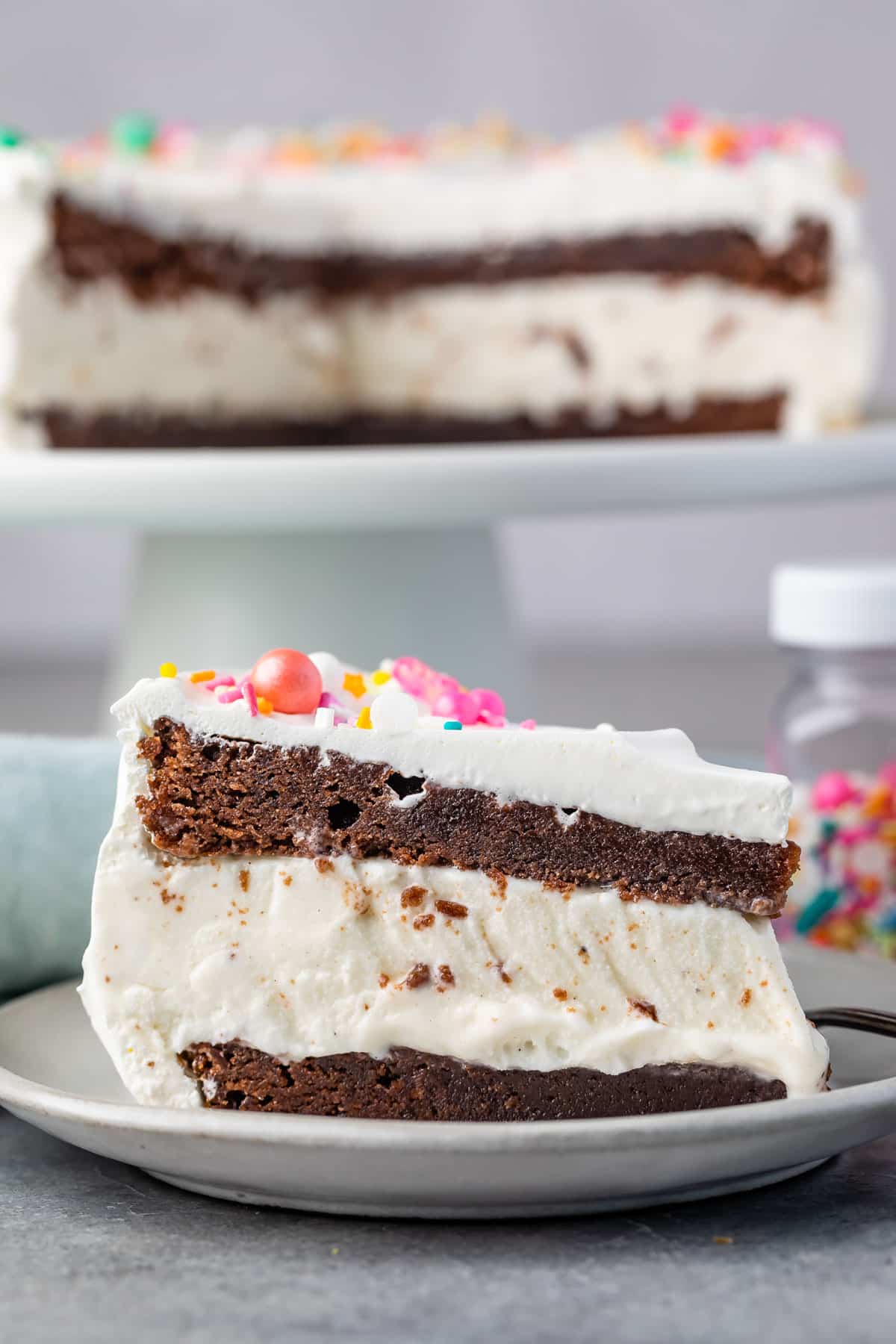 brownie cake layered with ice cream and frosting and topped with sprinkles.