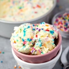 scooped ice cream with sprinkles mixed in, in pink and white stacked bowls.