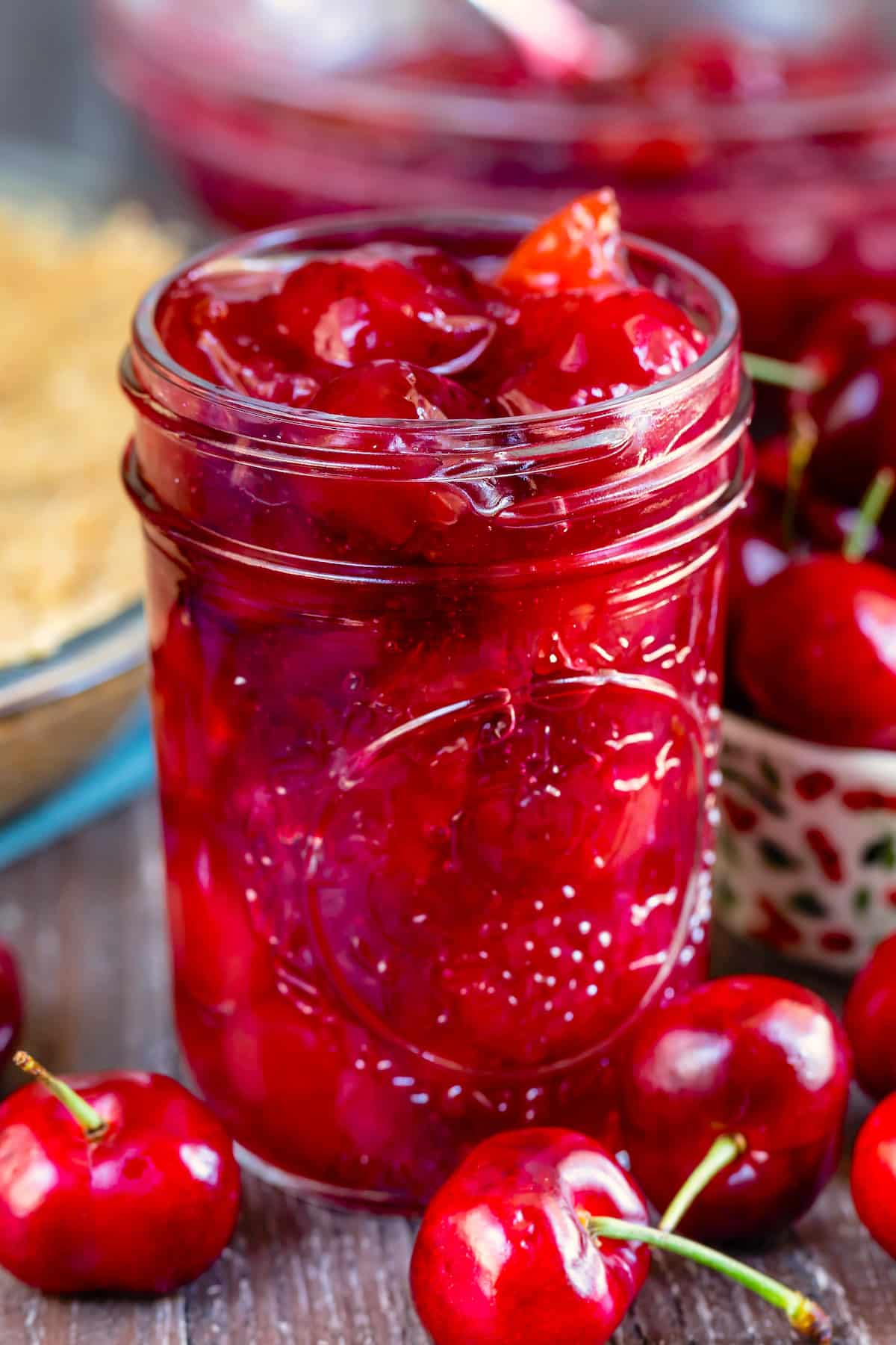 cherry pie in a clear mason jar surrounded by cherries.