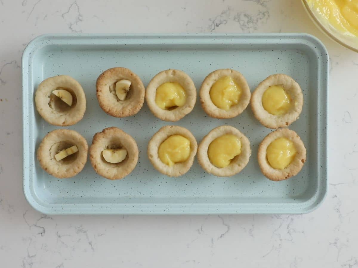 10 cookie cups on teal cookie sheet half with pudding and half with banana slices.