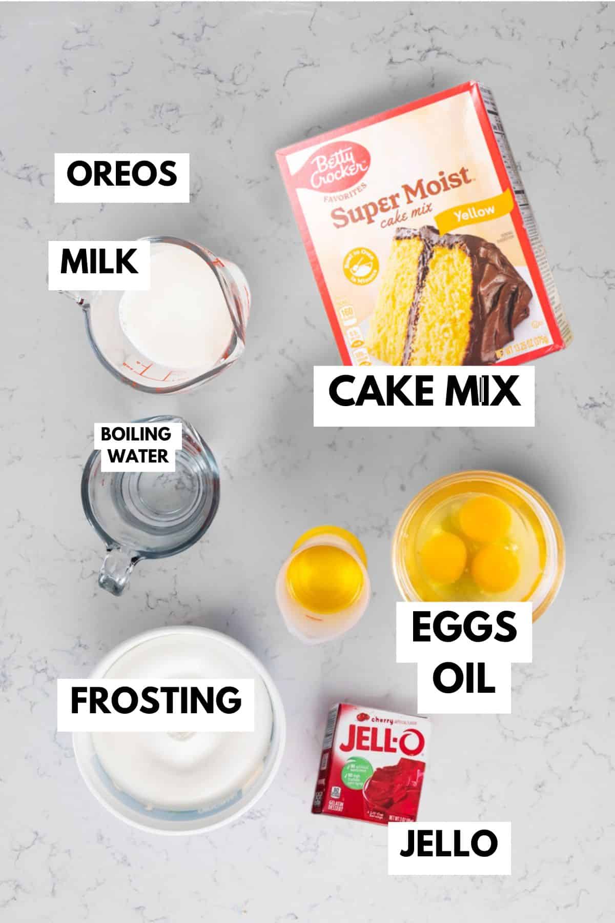Top-down view of labeled baking ingredients for a Jello Poke Cake on a counter: Oreos, milk, boiling water, yellow cake mix, eggs, oil, white frosting, and a box of red Jello.