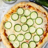 pizza with sliced zucchinis on top.