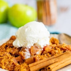 orange dump cake on a white plate with white ice cream on top.