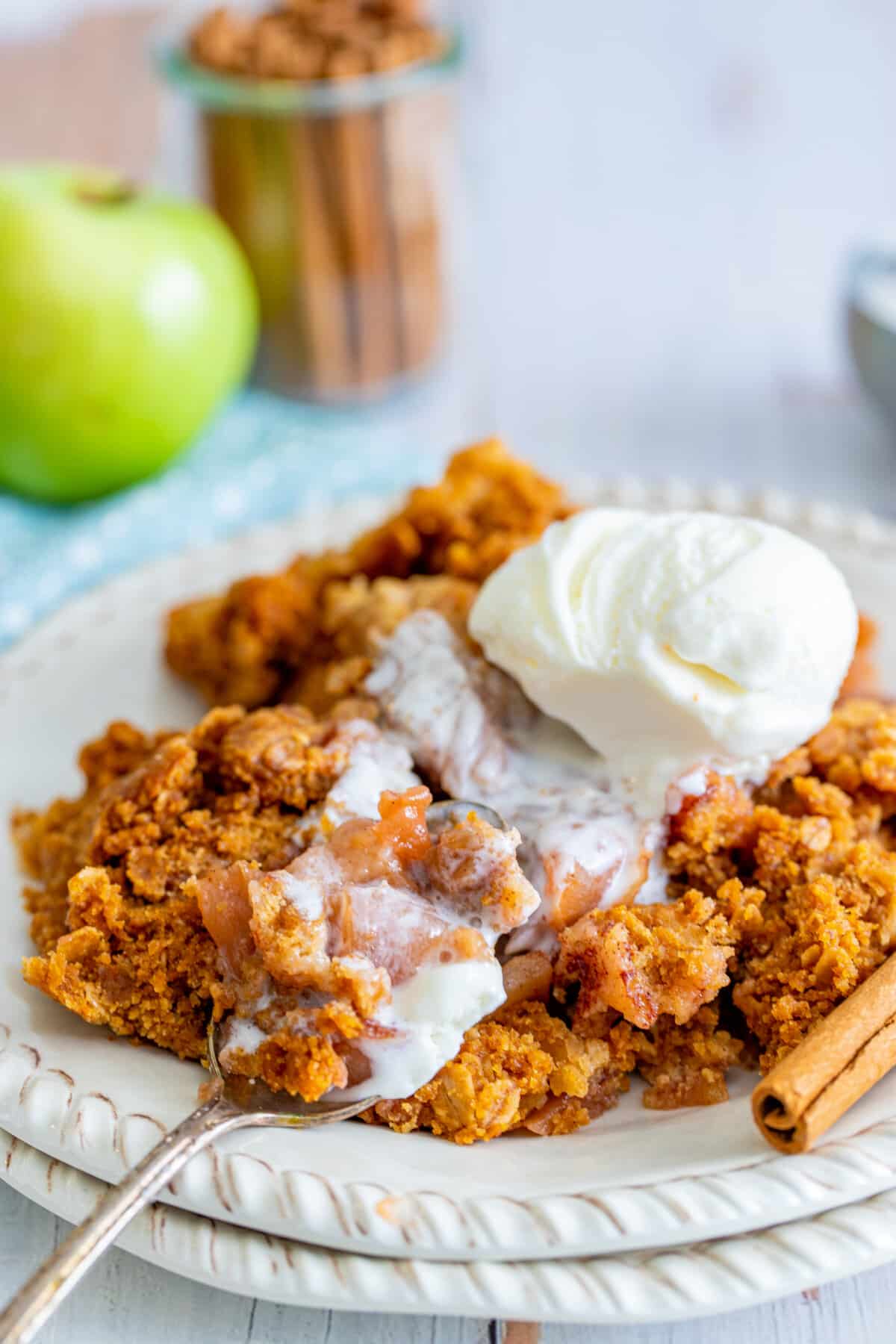 orange dump cake on a white plate with white ice cream on top.