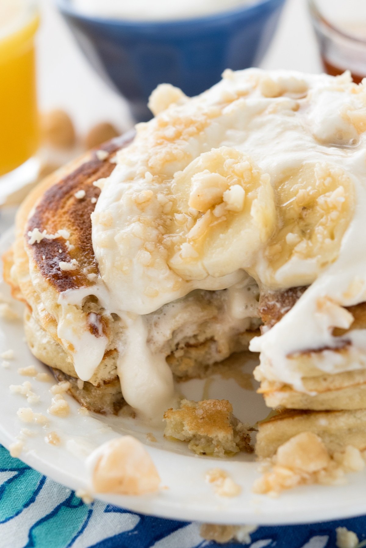 stacked pancakes on a white plate with banana slices on top.