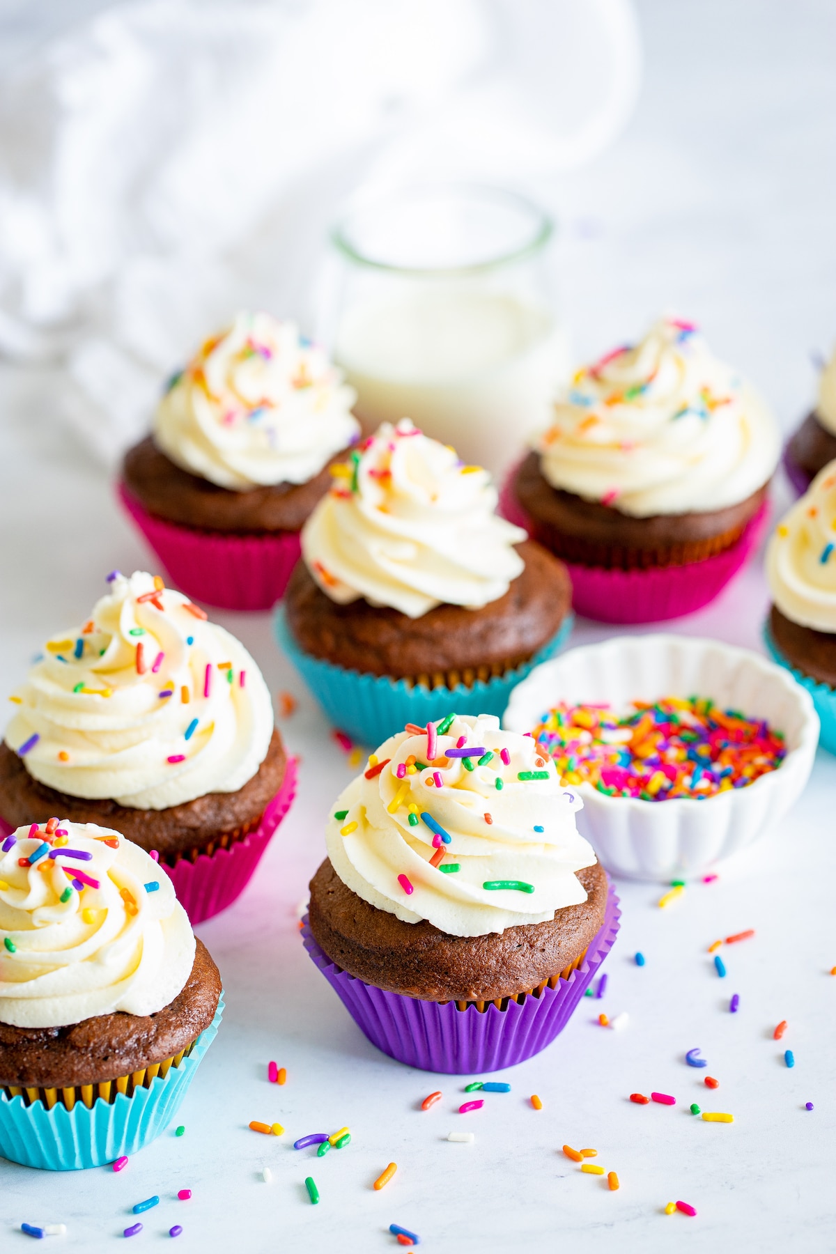 chocolate cupcake in colorful wrappers with vanilla frosting and colorful sprinkles.