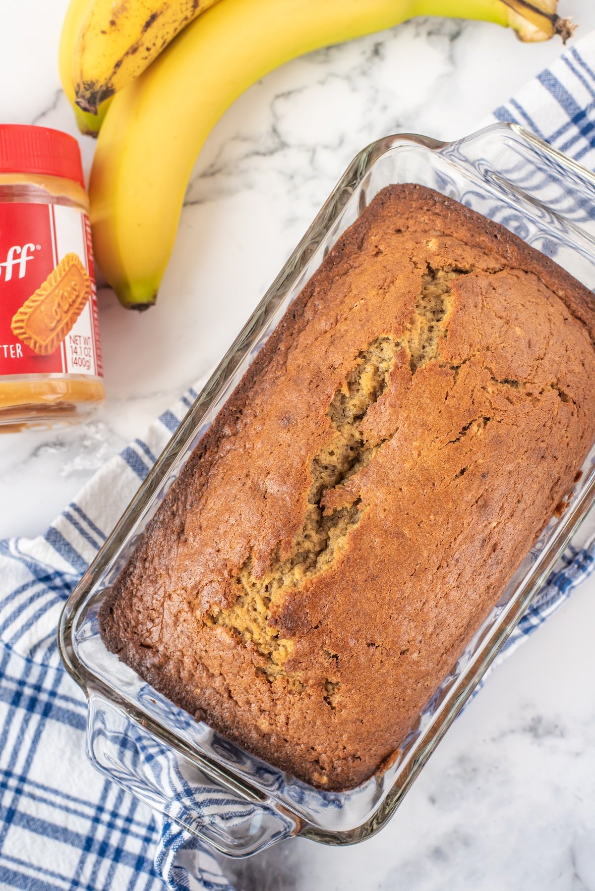 banana bread in a glass pan next to bananas.