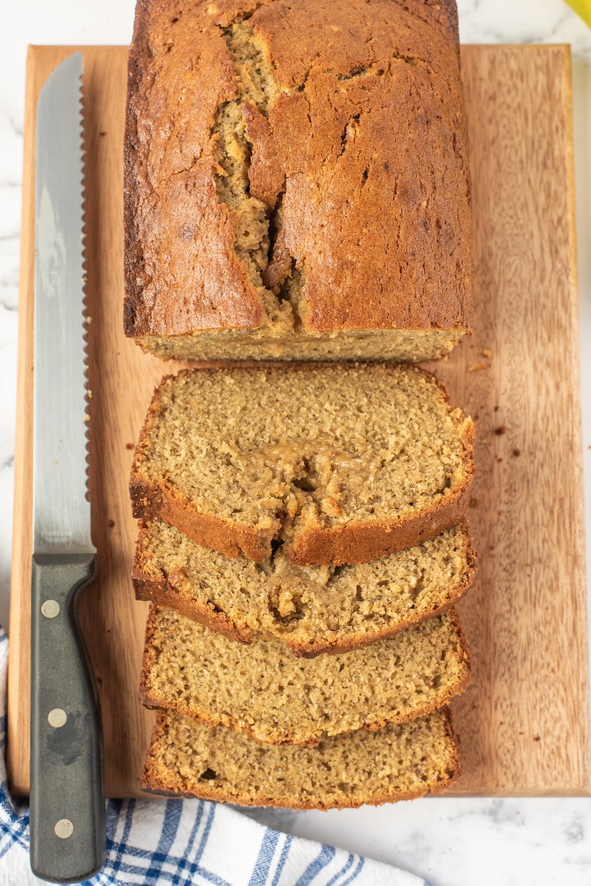 sliced banana bread next to a serrated knife on a cutting board.