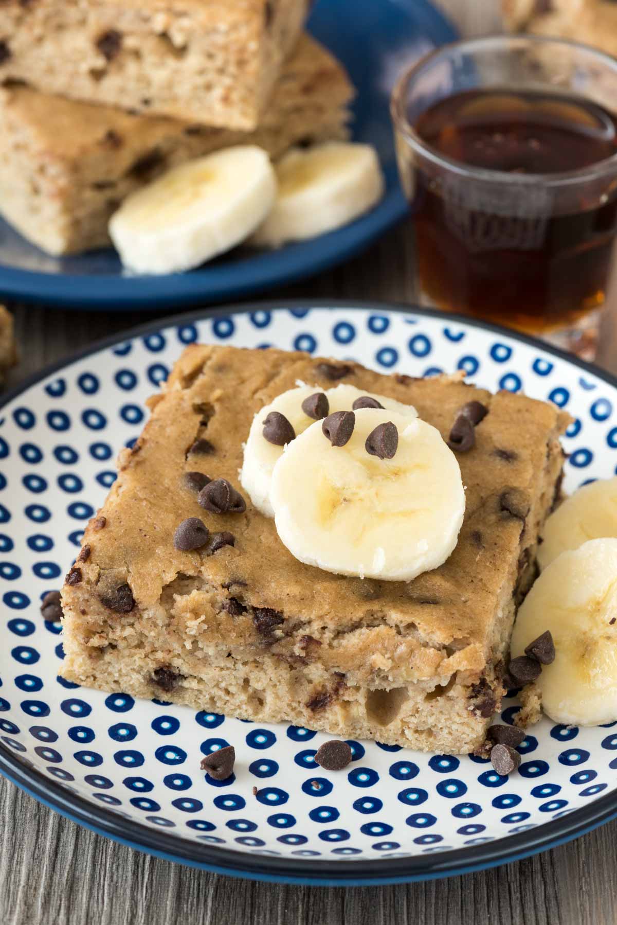 square slice of pancake with sliced bananas and chocolate chips on top.