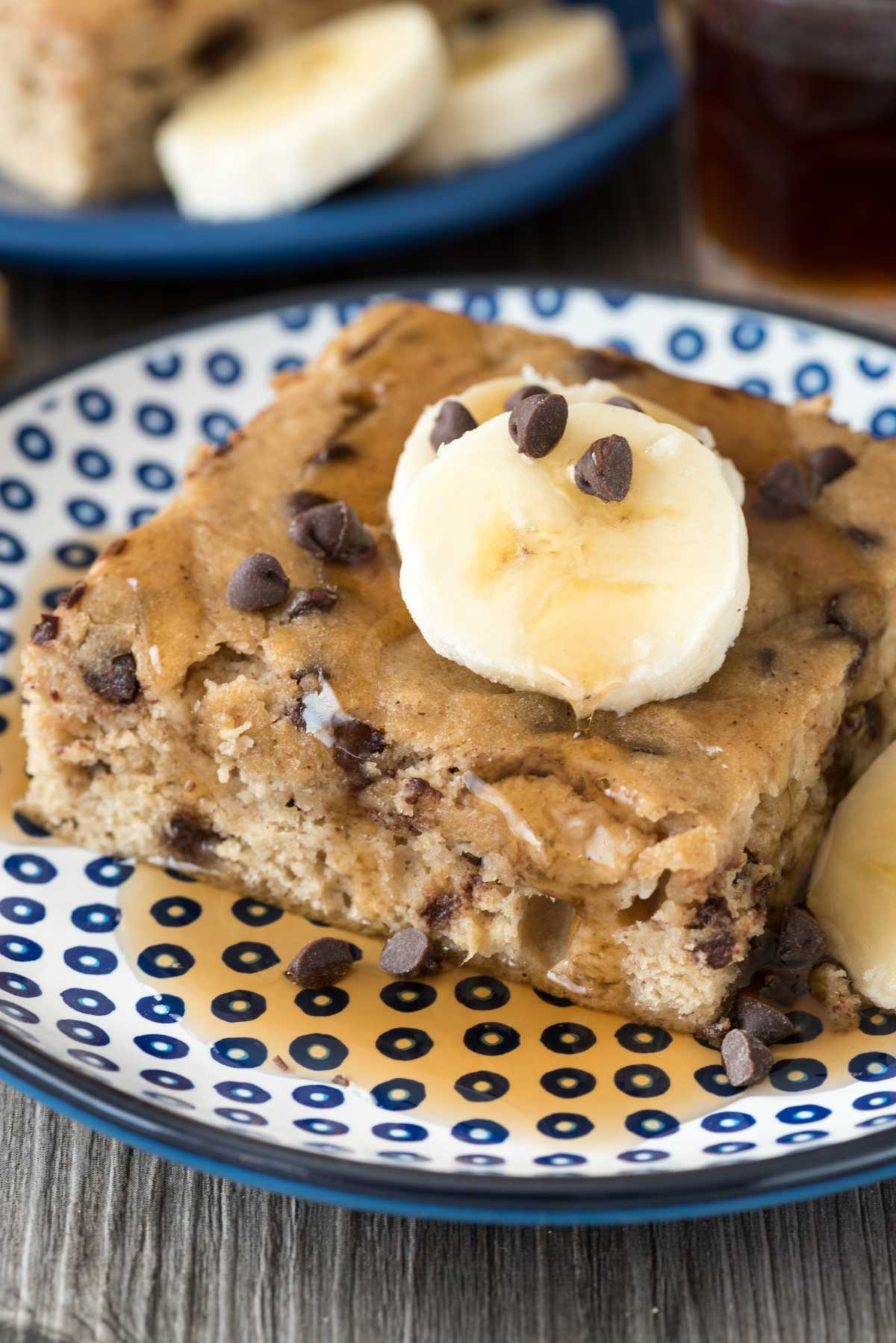 square slice of pancake with sliced bananas and chocolate chips on top.