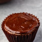ganache on top of a chocolate cupcake in brown cupcake wrappers.