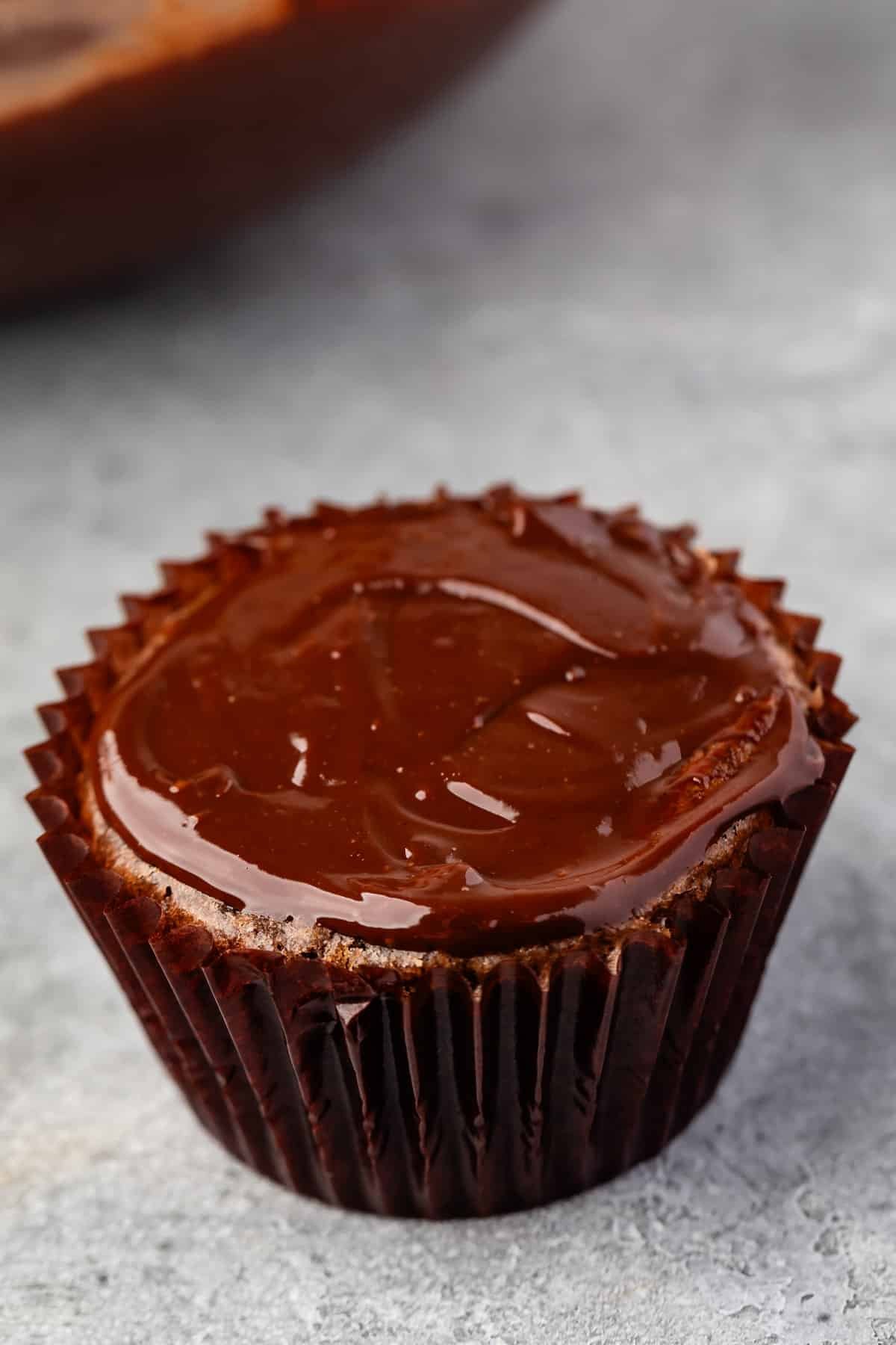 ganache on top of a chocolate cupcake in brown cupcake wrappers.