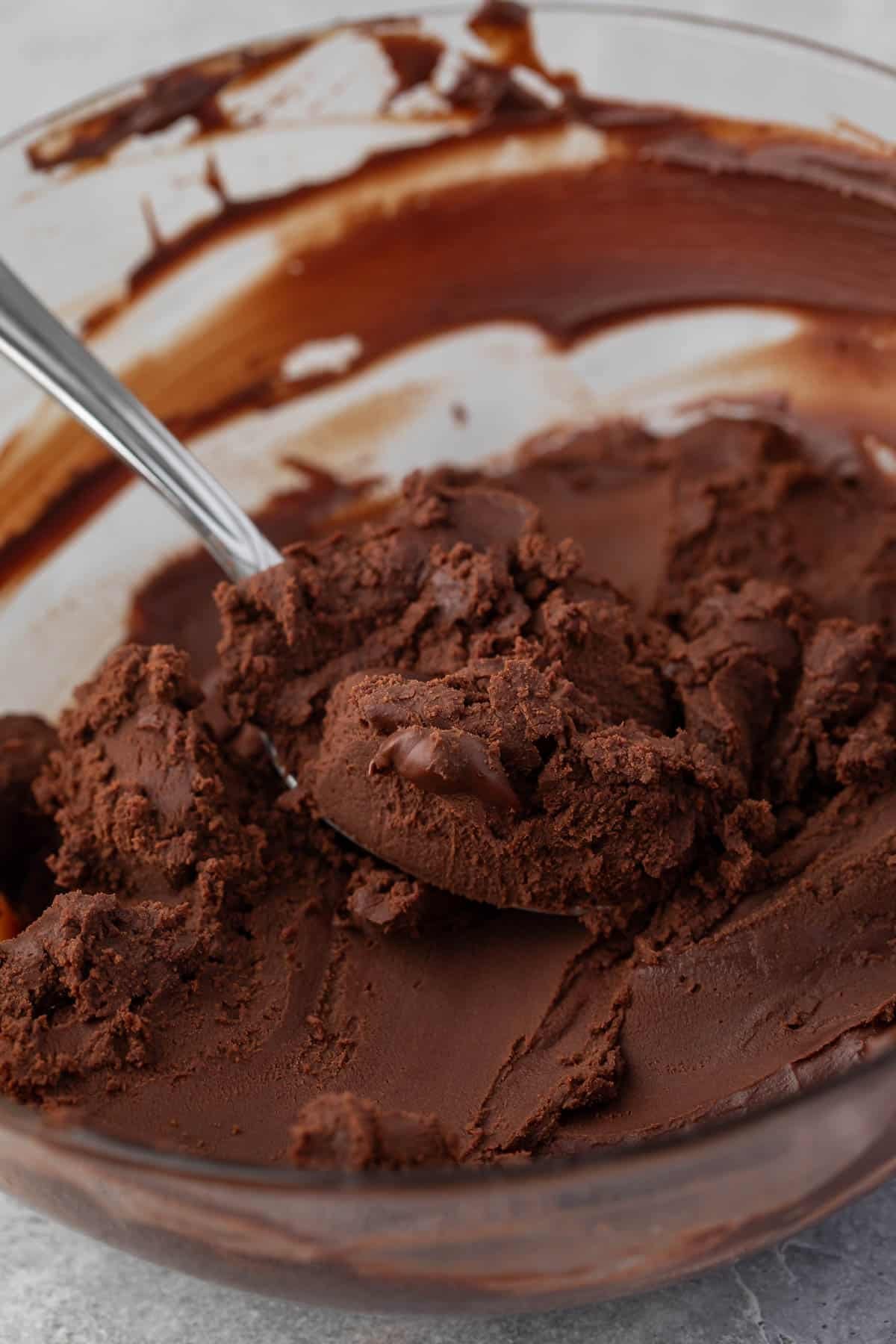 spoon scooping whipped ganache in a clear bowl.