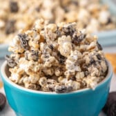 popcorn covered in melted chocolate and peanut butter in a teal bowl.