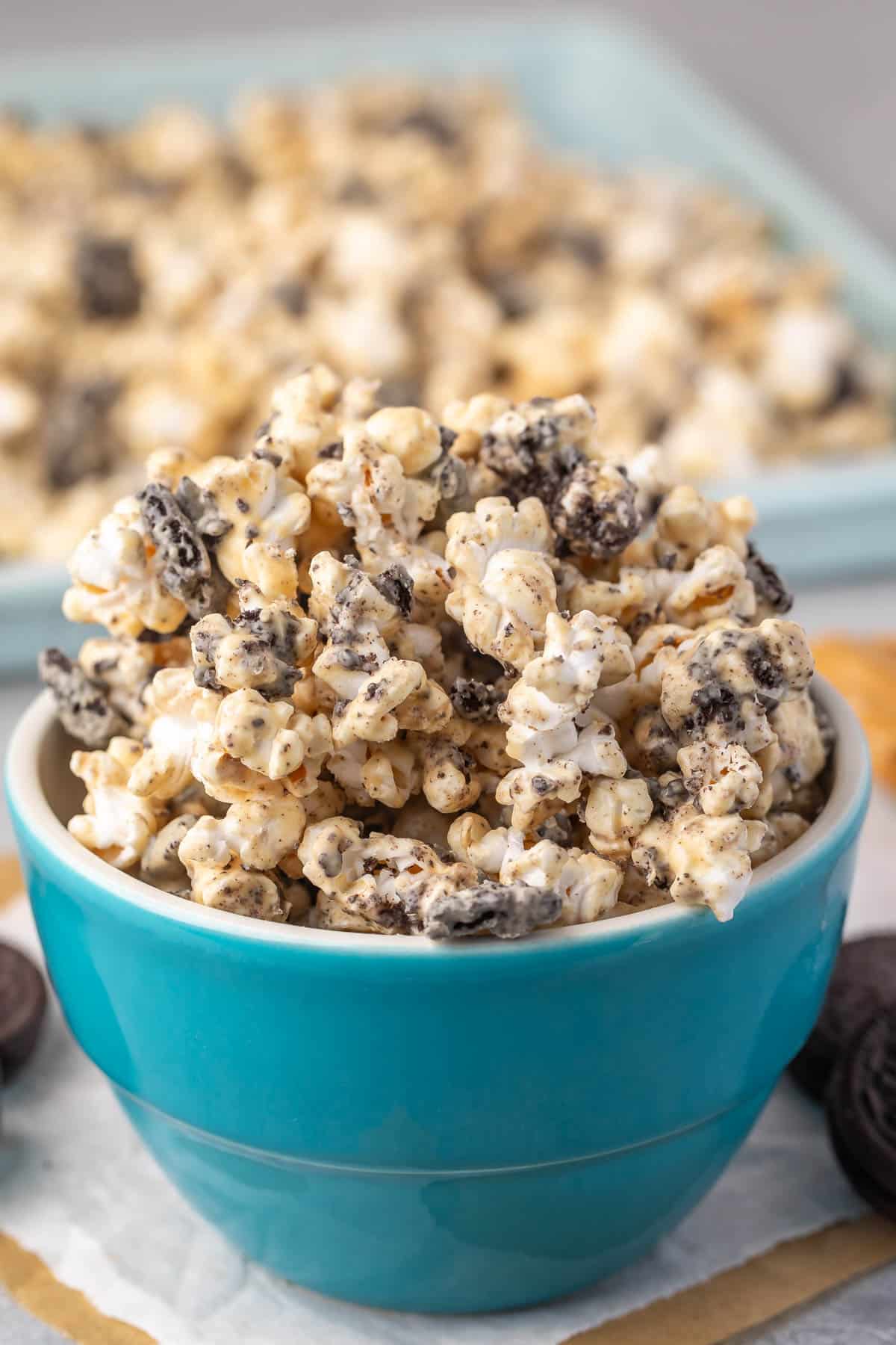 popcorn covered in melted chocolate and peanut butter in a teal bowl.