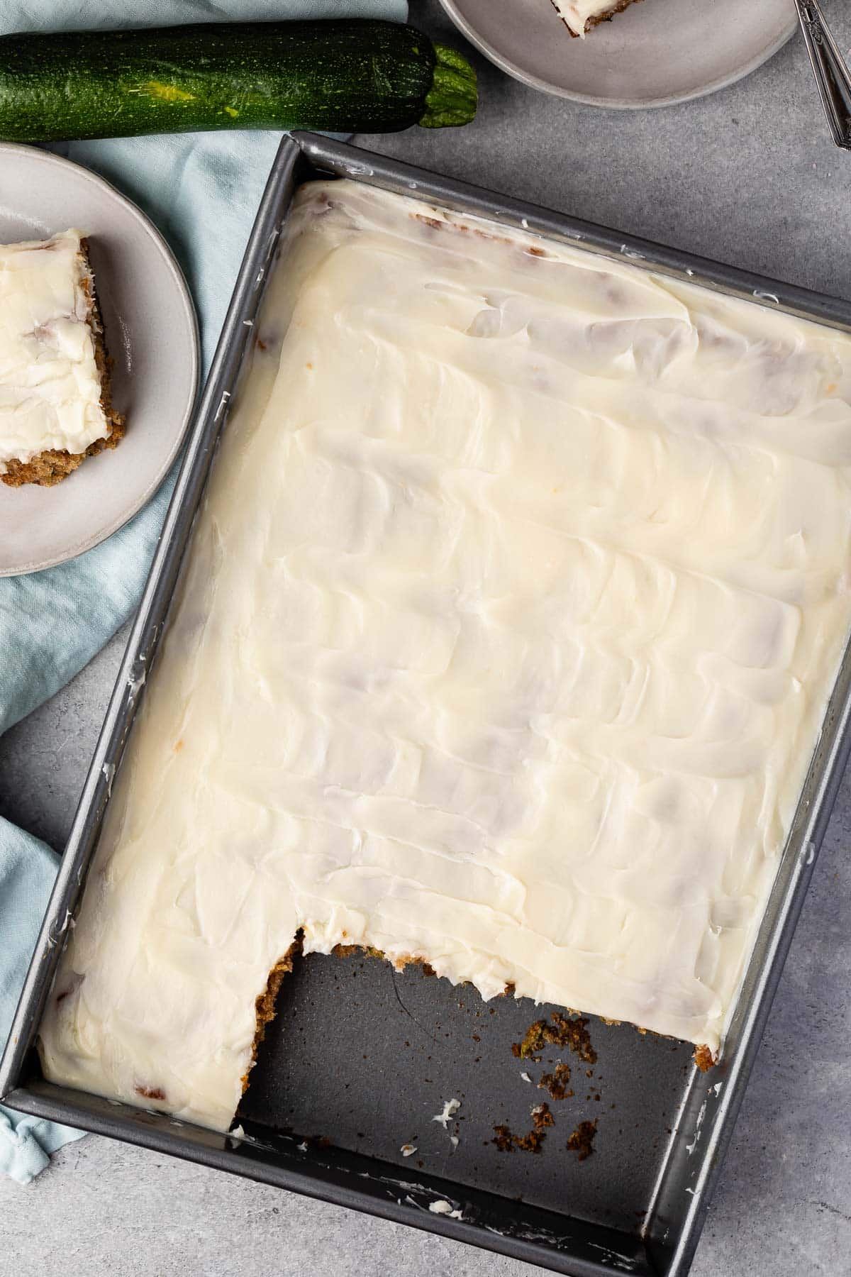 zucchini cake in a rectangle grey pan with a slice taken out.