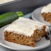 square slice of zucchini cake on a grey plate next to a fork.