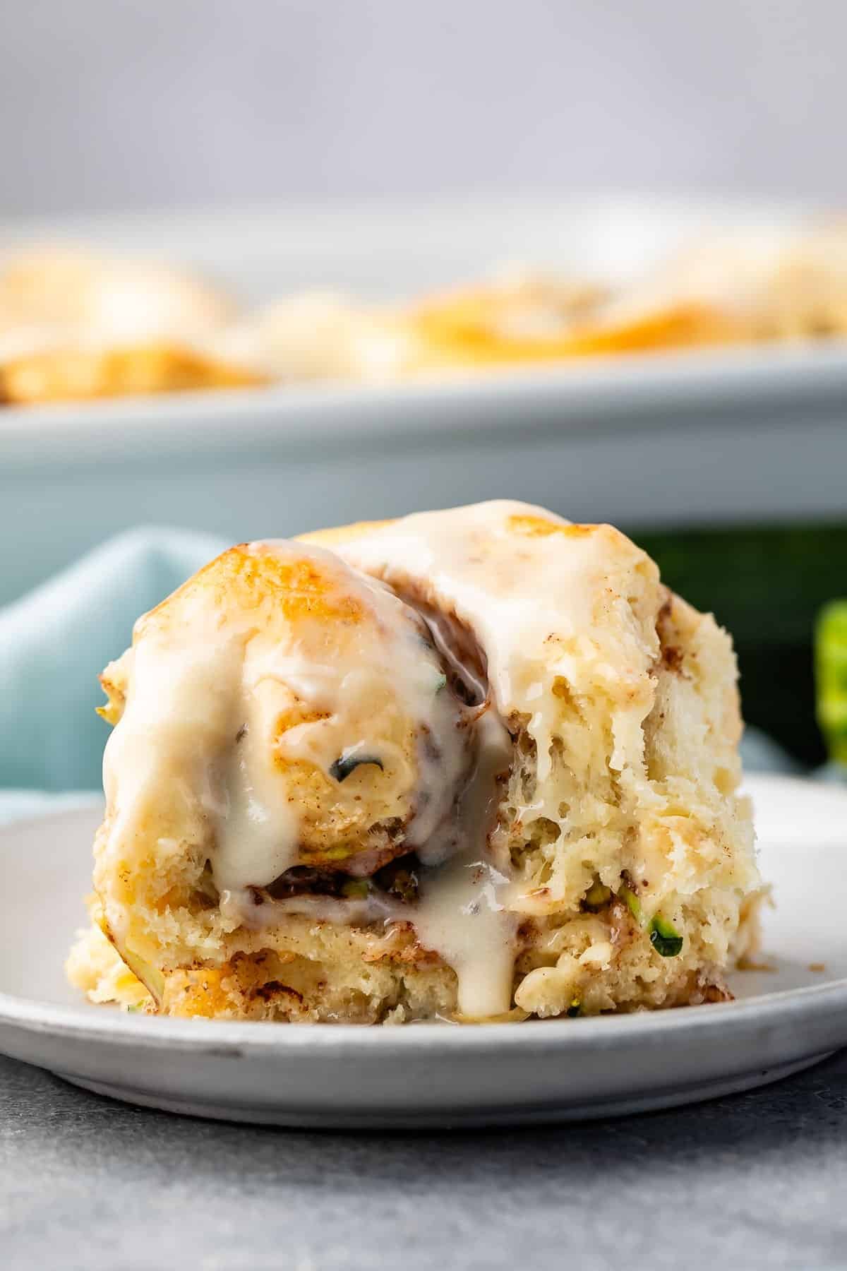 one cinnamon roll with frosting on top on a grey plate.